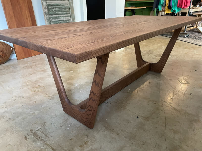 A mid-century style oak dining table with sculpted curved legs