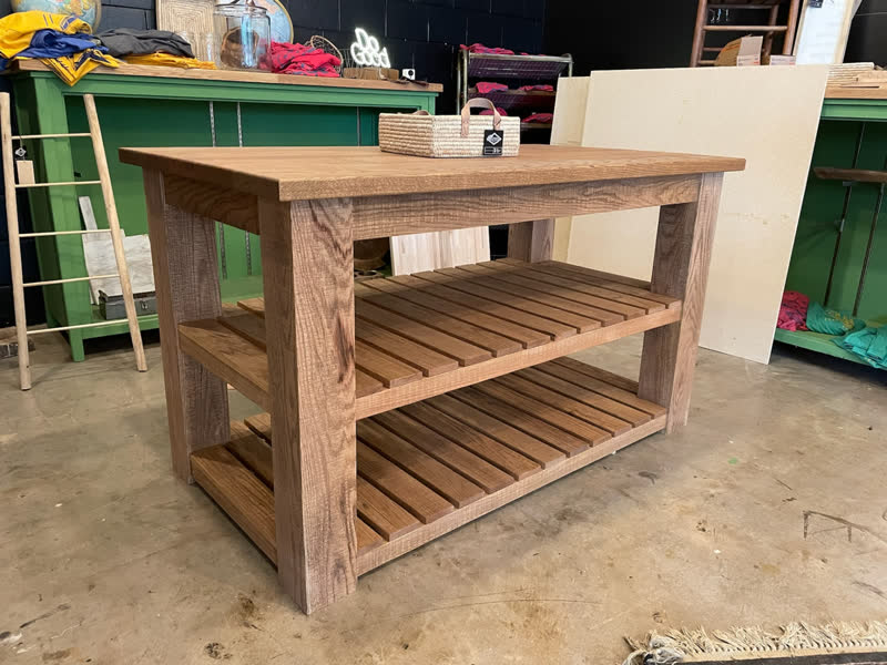 A rustic oak console with slatted lower shelves on display in the Mercy Goods shop