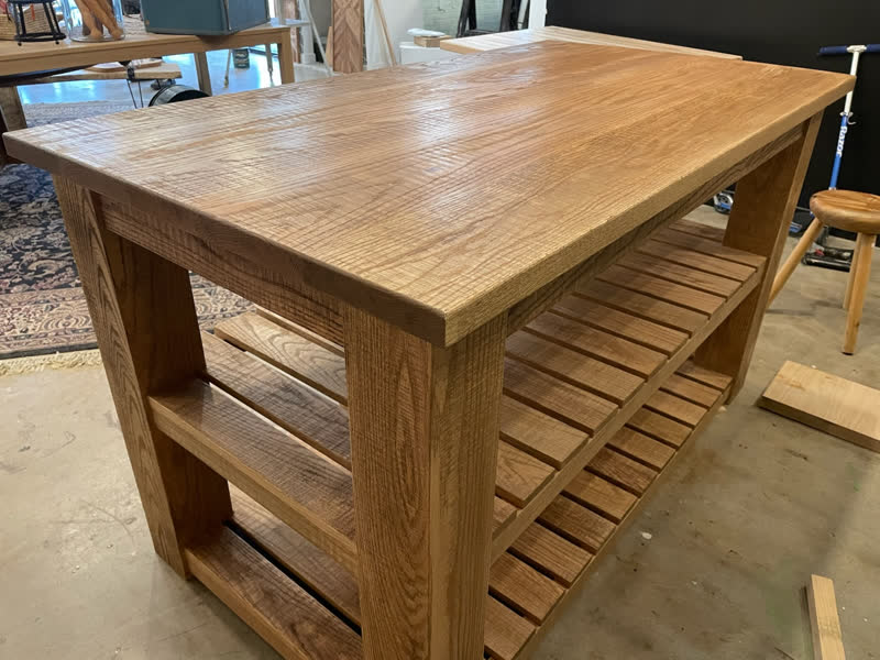 A rustic oak kitchen island with slatted storage shelves, fresh from the shop