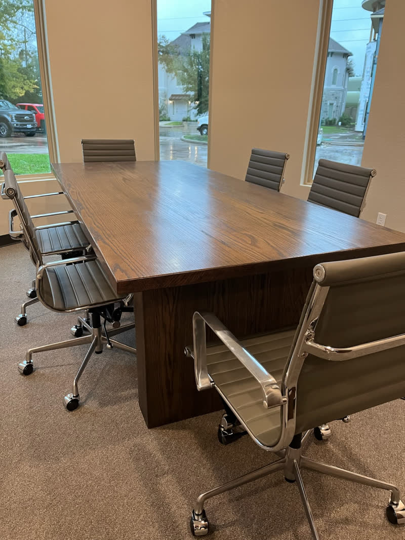 A dark oak conference table with a paneled base, installed in a client's office