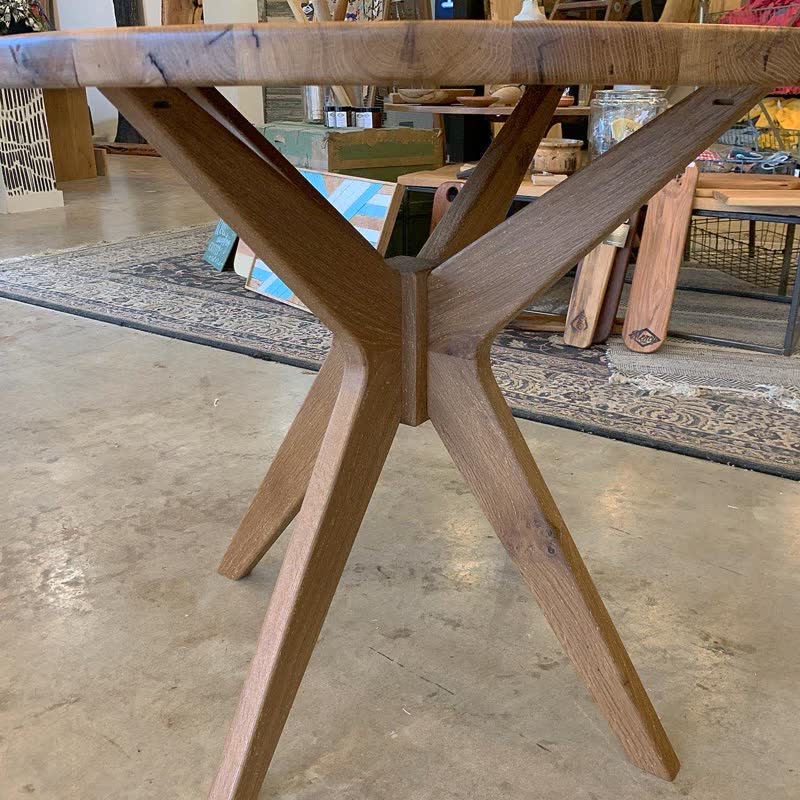 A round table with a hand-built crossed wooden pedestal base in the shop