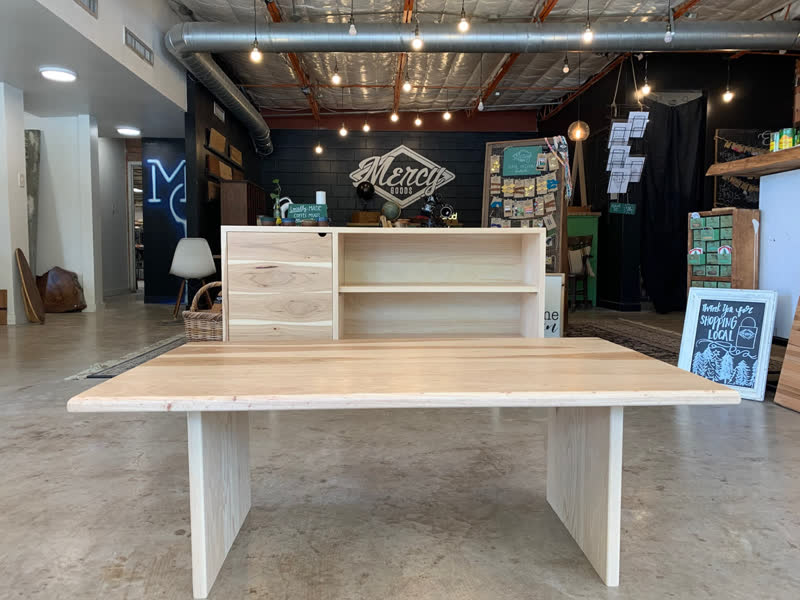 A matching light wood table and credenza set on the Mercy Goods retail floor