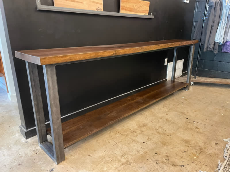 A walnut console table with a steel frame and lower shelf, in the shop