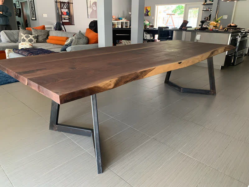 A long live-edge walnut dining table on angled steel legs in a client's home