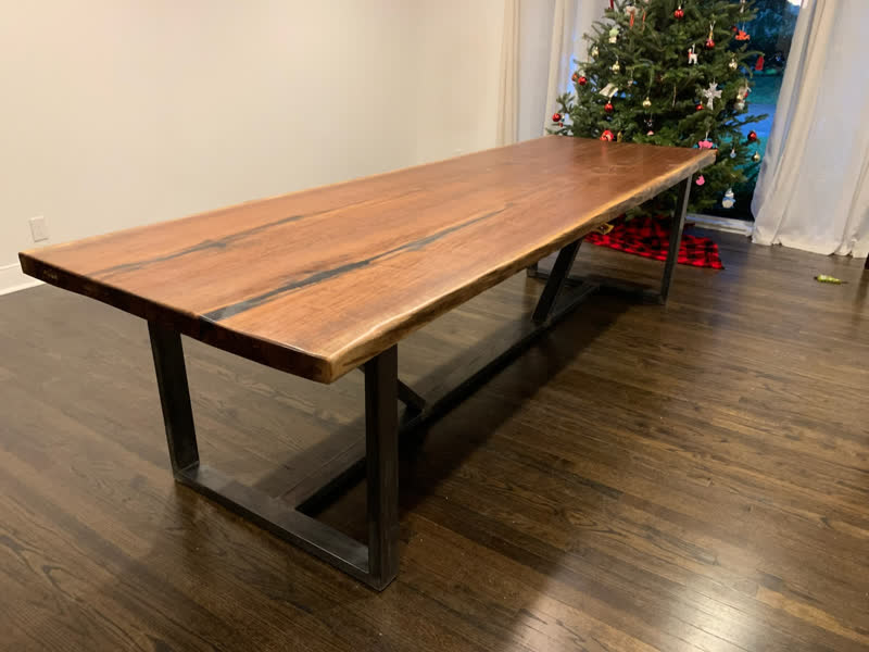 A live-edge walnut dining table on a black X-frame steel base, in a client's home